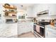 Bright kitchen with white cabinets, granite countertops, stainless oven and open shelves at 701 Creekside Dr, Clayton, NC 27520