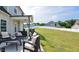 Backyard patio featuring dark outdoor seating with light cushions and a manicured, grassy lawn at 77 Redpine Ct, Clayton, NC 27520