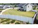Aerial view of large fenced backyard with a playset, patio with seating, and expansive grassy area at 77 Redpine Ct, Clayton, NC 27520