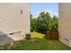 The backyard has a small grassy area, with trees in the background, enclosed by the neighboring home and a partial fence at 817 Stable Fern Dr, Fuquay Varina, NC 27526