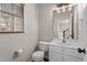 Cozy half bathroom with a white vanity, a window, and modern lighting fixtures at 8912 Erinsbrook Dr, Raleigh, NC 27617