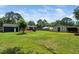 Large backyard features a spacious lawn, a wooden deck with seating, a greenhouse, and a storage building at 914 Forest Dr, Garner, NC 27529