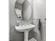 Elegant powder room with pedestal sink, oval mirror, and neutral gray walls at 9530 Vira Dr, Raleigh, NC 27617