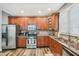 Kitchen with wood cabinets, granite countertops, tile backsplash, stainless-steel appliances, and wood-look floors at 9530 Vira Dr, Raleigh, NC 27617