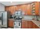 Close up of kitchen with wood cabinets, granite countertops, tile backsplash, and stainless-steel stove and microwave at 9530 Vira Dr, Raleigh, NC 27617