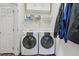 Functional laundry room with side-by-side washer and dryer, white cabinets, shelves, and white door at 9530 Vira Dr, Raleigh, NC 27617