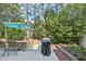 Inviting patio with an umbrella-covered dining set, lush landscaping, and a grill perfect for outdoor entertaining at 9530 Vira Dr, Raleigh, NC 27617