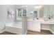 Bathroom featuring a soaking tub, dual sinks, vanity area, and a large window at 9612 Treymore Dr, Raleigh, NC 27617
