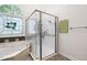 Bright bathroom featuring a glass shower, tub with decorative window, and neutral color palette at 101 Deerwalk Ct, Cary, NC 27513