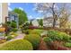 Backyard with garden, flowering plants, mature trees, manicured bushes and a white iron bench at 1012 Delta River Way, Knightdale, NC 27545