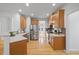 A kitchen features wooden cabinetry, stainless steel appliances, and hardwood flooring, illuminated by recessed lighting at 1012 Delta River Way, Knightdale, NC 27545