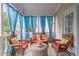 Inviting screened porch with wicker furniture and blue curtains creating a relaxing atmosphere at 1012 Delta River Way, Knightdale, NC 27545