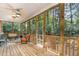 Relaxing screened-in porch with wooden floors, ceiling fan, and views of the surrounding woods at 109 Jasmine Rose Ct, Holly Springs, NC 27540