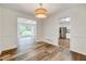 Dining room with wood floors, modern light fixture, and doorway views to the living room and kitchen at 1209 Locharron Ln, Cary, NC 27511