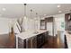 A kitchen island with sink, dark cabinets, and open floor plan with a staircase at 125 Durban Meadow Dr, Holly Springs, NC 27540