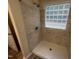 Tiled walk-in shower featuring glass block window and a new shower head and faucet at 125 Tast Dr, Wendell, NC 27591