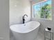 Luxurious bathroom featuring a freestanding tub, modern fixtures, and a serene outdoor view; spa-like retreat at 129 Grande Dr, Morrisville, NC 27560