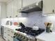 Gourmet kitchen featuring modern stainless steel appliances, white cabinets, and stylish backsplash at 129 Grande Dr, Morrisville, NC 27560