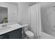 Bright bathroom with white countertops, dark blue vanity, toilet, and bathtub with white shower curtain at 1534 Millrock Trl, Wendell, NC 27591