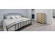 A light-filled bedroom with a metal bed frame, carpet and a wood dresser at 1534 Millrock Trl, Wendell, NC 27591