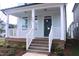 Inviting front porch with white railings, wooden steps, and a stylish blue front door at 1534 Millrock Trl, Wendell, NC 27591