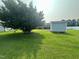 A large tree shades the backyard along with a storage shed and partial view of the house at 202 Camelia Dr, Princeton, NC 27569