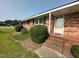 Close up of a brick home's entrance, showing steps, landscaping, and a storm door at 202 Camelia Dr, Princeton, NC 27569