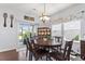 Sunlit dining room features dark wood floors, decorative chandelier, and backyard access at 209 Sage Oak Ln, Holly Springs, NC 27540