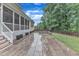 Backyard with stone patio, leads to the home's screened-in porch; landscaped for relaxation and entertainment at 216 Pondside Dr, Apex, NC 27539