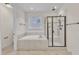 Modern bathroom with a separate glass shower, soaking tub, and neutral tiling throughout at 216 Pondside Dr, Apex, NC 27539