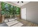 View of a covered back porch with wooden floors, white door, and wooden railing surrounded by lush greenery at 2623 Broad Oaks Pl, Raleigh, NC 27603