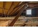 View of attic insulation and wood framing, including a window at 2710 Broad St, Durham, NC 27704
