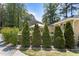 The home's backyard features a stone-lined flower bed with shrubbery and trimmed evergreen trees at 2710 Broad St, Durham, NC 27704