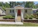 Charming single-story home featuring a red front door, white railings, brick foundation trim, and a well-manicured lawn at 2710 Broad St, Durham, NC 27704