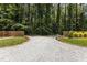 Long gravel driveway leading to a wooded area, bordered by manicured lawn and wooden fencing at 2712 Broad St, Durham, NC 27704