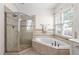 Bright bathroom featuring a tiled shower, soaking tub, and a window providing natural light at 3004 Montville Valley Ct, Cary, NC 27519