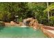 Backyard pool area featuring a rock waterfall, mature trees and landscaping at 3004 Montville Valley Ct, Cary, NC 27519