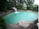 Backyard pool with a rock waterfall feature surrounded by lush trees at 3004 Montville Valley Ct, Cary, NC 27519
