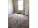 Neutral bedroom showcasing soft carpeting, a bright window, and a classic white door with paneled detailing at 305 Theys Mill, Fuquay Varina, NC 27526