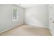 A simple bedroom featuring neutral carpet, a window with blinds, and white walls at 3303 Glen Currin Dr, Raleigh, NC 27612