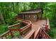 Secluded brown two-story home featuring an expansive wooden deck and lush, mature trees surrounding the property at 3416 Ocotea St, Raleigh, NC 27607