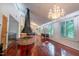 Living room featuring hardwood floors, a brick fireplace, chandelier, and large windows overlooking an outdoor space at 3416 Ocotea St, Raleigh, NC 27607
