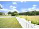 Large backyard with a white picket fence bordering a lush field, providing ample privacy and space at 3684 Ben Mil Ct, Franklinton, NC 27525