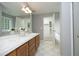 Bathroom with dual sinks, a large mirror, white tile floor and an open door to tub area at 3684 Ben Mil Ct, Franklinton, NC 27525