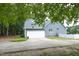 View of the home's exterior featuring a gray siding, white garage door, and mature trees at 3684 Ben Mil Ct, Franklinton, NC 27525