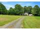 A gravel driveway leading to a charming home with a spacious front yard at 4524 Sugar Maple Rd, Oxford, NC 27565