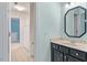 Bathroom with octagonal mirror and a single sink vanity with dark cabinets at 4724 Ludwell Branch Ct, Raleigh, NC 27612