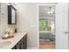 Bathroom with double sinks leading to a bedroom with natural light from large windows at 4724 Ludwell Branch Ct, Raleigh, NC 27612