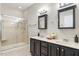 Well-lit bathroom with a glass enclosed shower and dual sink vanity with dark cabinets at 4724 Ludwell Branch Ct, Raleigh, NC 27612