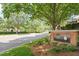 Landscaped entrance to the community with a brick sign framed by lush trees and greenery at 4724 Ludwell Branch Ct, Raleigh, NC 27612